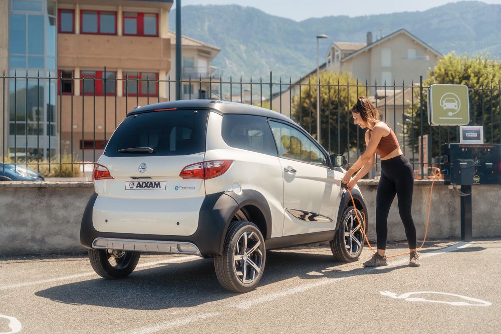 Chica cargando su coche sin carnet eléctrico AIXAM