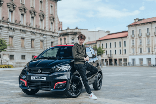 El coche sin carnet AIXAM City en color negro con acabados en rojo. Un chico menor de edad conduciendo.